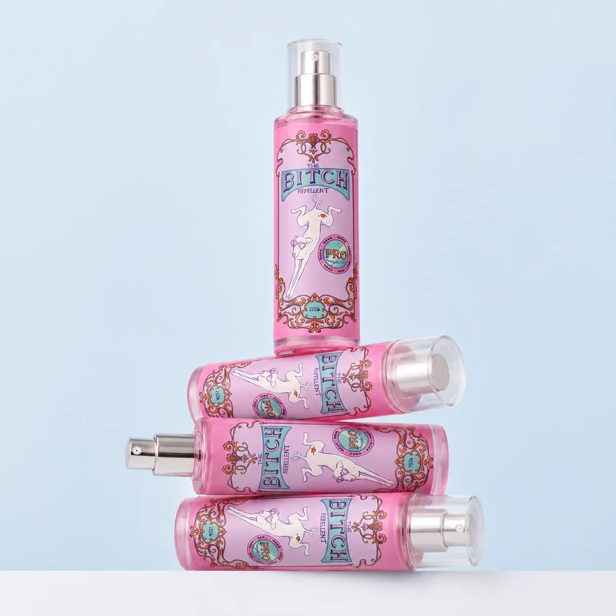 Cuatro sprays Bitch Repellent apilados, uno de pie sobre tres tumbados, contra una pared azul claro